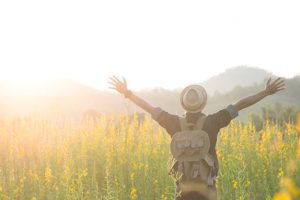 Vrouw met uitgestrekte armen op een veld bij blog door coach voor eigenwaarde, rust, kracht en zelfvertrouwen "Maak je droom waar".
